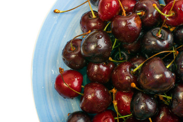 Fresh Overripe ripe Cherries on Blue Rustic Plate Top View