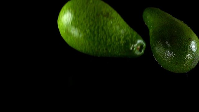 Falling of avocado on a black background. Slow motion.