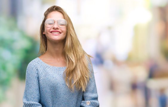 Young beautiful blonde woman wearing sweater and glasses over isolated background with a happy and cool smile on face. Lucky person.