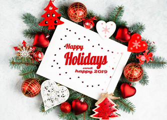 Fototapeta na wymiar Happy Holidays and happy 2019 text with Christmas photoframe surrounded by branches of a New Year tree, red Christmas decorations with copy space. Top view, flat lay.