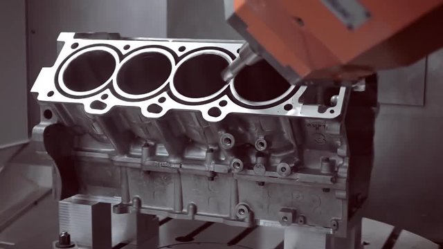 The robot's arm on the program performs the milling of the cylinder block of the internal combustion engine
