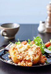 A baked potato topped with baked beans and cheese, served with a salad