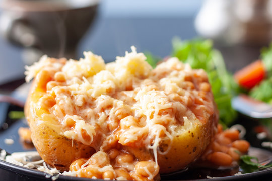 A baked potato topped with baked beans and cheese, served with a salad