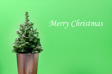 Mini Christmas tree on green background. Minimalistic concept.