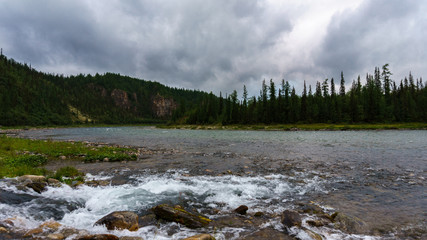 The river with a rapid current. Rocky shore. Cloudy sky. Landscape. Ural. Russia