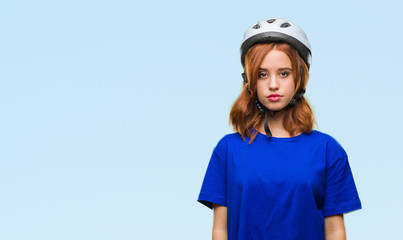 Young beautiful woman wearing cyclist helmet over isolated background with serious expression on face. Simple and natural looking at the camera.