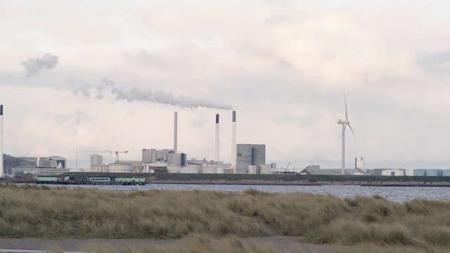 wind turbine beside a powerplant on amager beach denmark. windmill. green energy wind energy