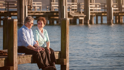 Seniorenpaar sitzend am Steg in der Abendsonne