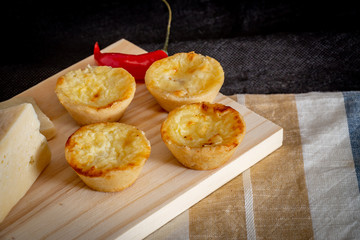 Homemade mini quiche with cheese on rustic background.