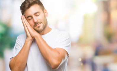 Obraz premium Young handsome man over isolated background sleeping tired dreaming and posing with hands together while smiling with closed eyes.