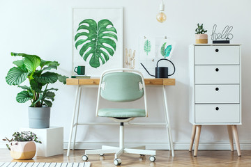 Stylish scandinavian home office desk with mock up poster frames, a lot of plants and office accessories. Brown wooden parquet and white backgrounds wall. Modern composition of homeoffice desk. - obrazy, fototapety, plakaty