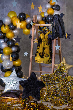 Decoration of golden party dress with leather jacket hanging on wooden hanger in club studio decorations.