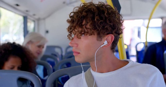 Male commuter listening music on earphones while travelling in bus 4k