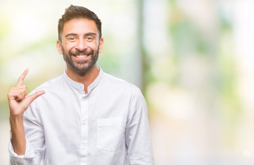 Adult hispanic man over isolated background smiling and confident gesturing with hand doing size sign with fingers while looking and the camera. Measure concept.