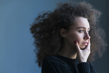 Portrait of depressed young brunette woman near window at home. Sadness, nostlagic, depression.