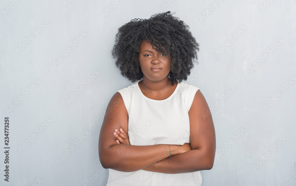 Poster Young african american woman over grey grunge wall skeptic and nervous, disapproving expression on face with crossed arms. Negative person.