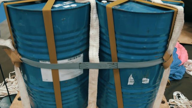 On the wooden pallet there are four metal barrel tied by strap with a laid parachute , ready to be dropped from an airplane. Shot in motion