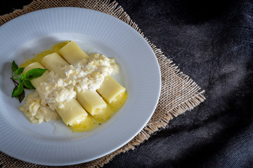 Italian caneloni with bechamel sauce and cheese on rustic background.