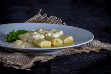 Italian caneloni with bechamel sauce and cheese on rustic background.