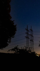 Nachthimmel mit Sternen am Wald mit Stromleitungen