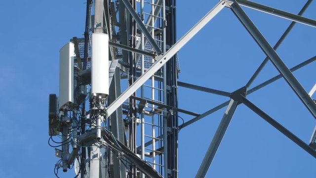 Communication tower with cellphone receivers and transmitters. White clouds and blue sky. Detail. Ontario, Canada.