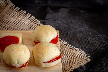 Brazilian homemade cheese bread AKA 'pao de queijo’, stuffed with guava dessert, on a rustic background.