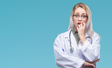 Young blonde doctor woman over isolated background looking stressed and nervous with hands on mouth biting nails. Anxiety problem.