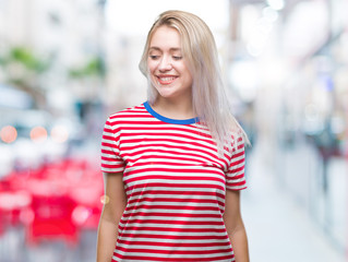 Young blonde woman over isolated background looking away to side with smile on face, natural expression. Laughing confident.