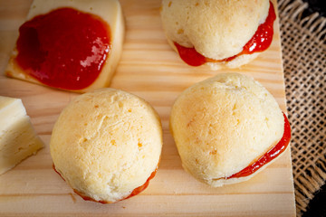 Brazilian homemade cheese bread AKA 'pao de queijo’, stuffed with guava dessert, on a rustic background.