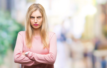 Young beautiful blonde woman wearing pink winter sweater over isolated background skeptic and nervous, disapproving expression on face with crossed arms. Negative person.