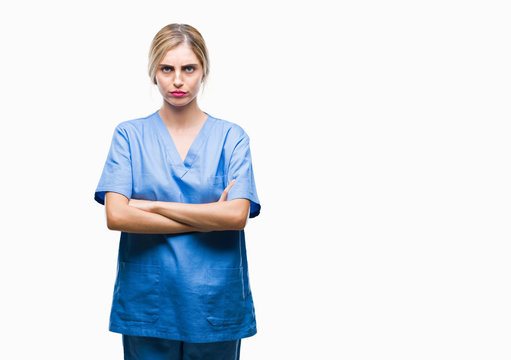 Young beautiful blonde doctor surgeon nurse woman over isolated background skeptic and nervous, disapproving expression on face with crossed arms. Negative person.