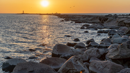 breakwater in the sea with red lighthouse at the end