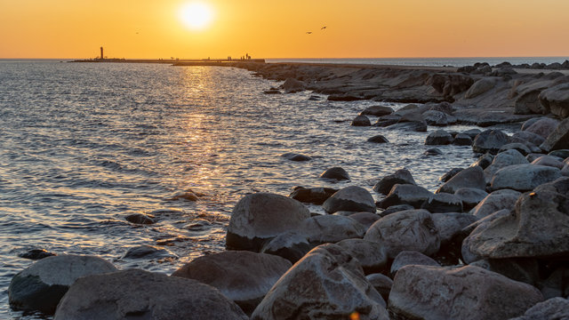 breakwater in the sea with red lighthouse at the end