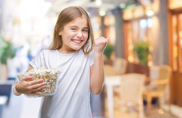 Young beautiful girl eating popcorn snack isolated background screaming proud and celebrating victory and success very excited, cheering emotion