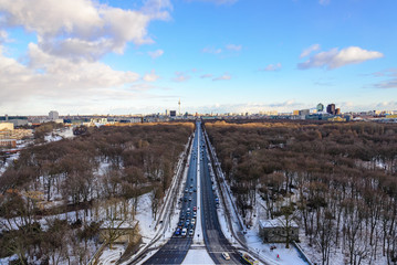 Aerial panoramic view of cityscape of Berlin skyline and scenery of trees without leaves in winter season at Tiergarten park from above at Victory Column with background of dusk sunset sky.