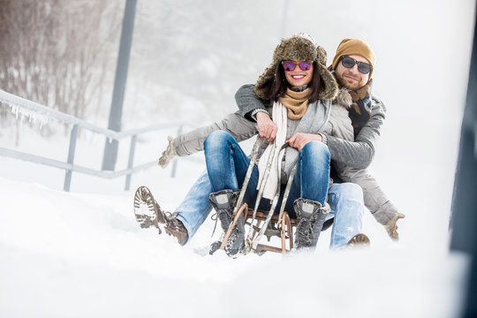 Young couple on sledge in winter outdoors