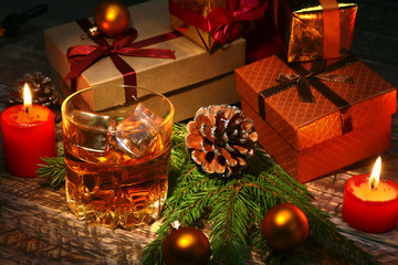 Cognac or whiskey in glass. Christmas balls, gift boxes and candles. New Year's tree, balls and glass with alcohol.