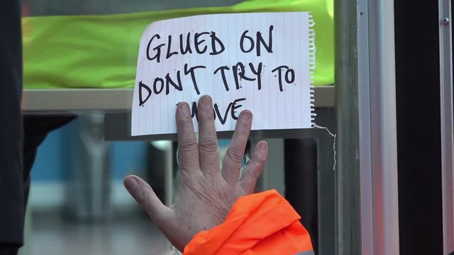 UK November 2018 - An environmental protestor superglues her hand with a note that says &sbquo;&Auml;&uacute;glued on, don&sbquo;&Auml;&ocirc;t try to move&sbquo;&Auml;&ugrave; to a window of the UK government Department for Energy offices.