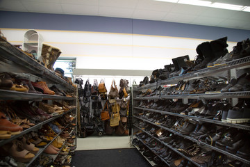 Isolated view of neutral colored womens pumps, shoes, sandals and purses on thrift store shelves and display - focus on purse display on back wall