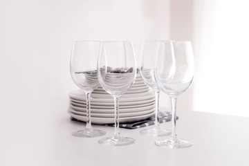Stack of clean dishes and glasses on table in kitchen