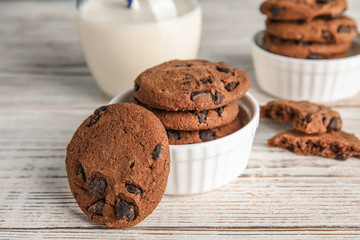Bowl with tasty chocolate chip cookies on wooden table