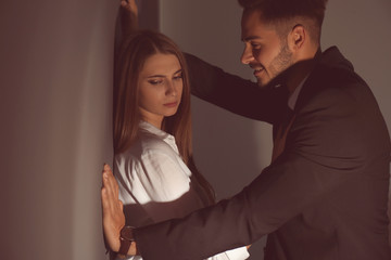 Boss molesting his female secretary on dark background. Sexual harassment at work