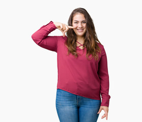 Beautiful plus size young woman over isolated background Pointing with hand finger to face and nose, smiling cheerful