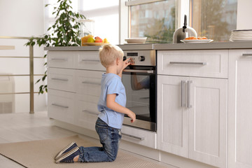 Little boy baking something in oven at home