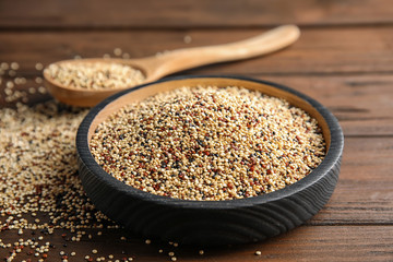 Plate with mixed quinoa seeds on wooden table