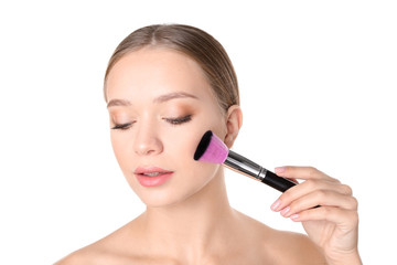 Portrait of beautiful young woman with makeup brush on white background