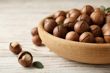 Plate with organic Macadamia nuts and space for text on wooden background