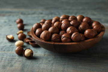 Plate with organic Macadamia nuts on blue wooden background
