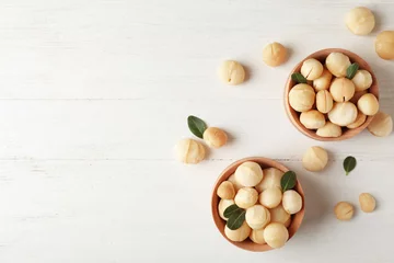 Fototapeten Bowls with shelled organic Macadamia nuts and space for text on white table, top view © New Africa