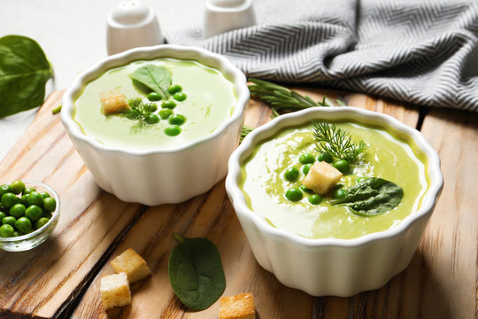 Fresh vegetable detox soup made of green peas and spinach with croutons served on board